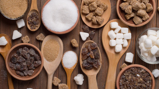 Various wooden spoons holding various kinds of sugar on a wooden table